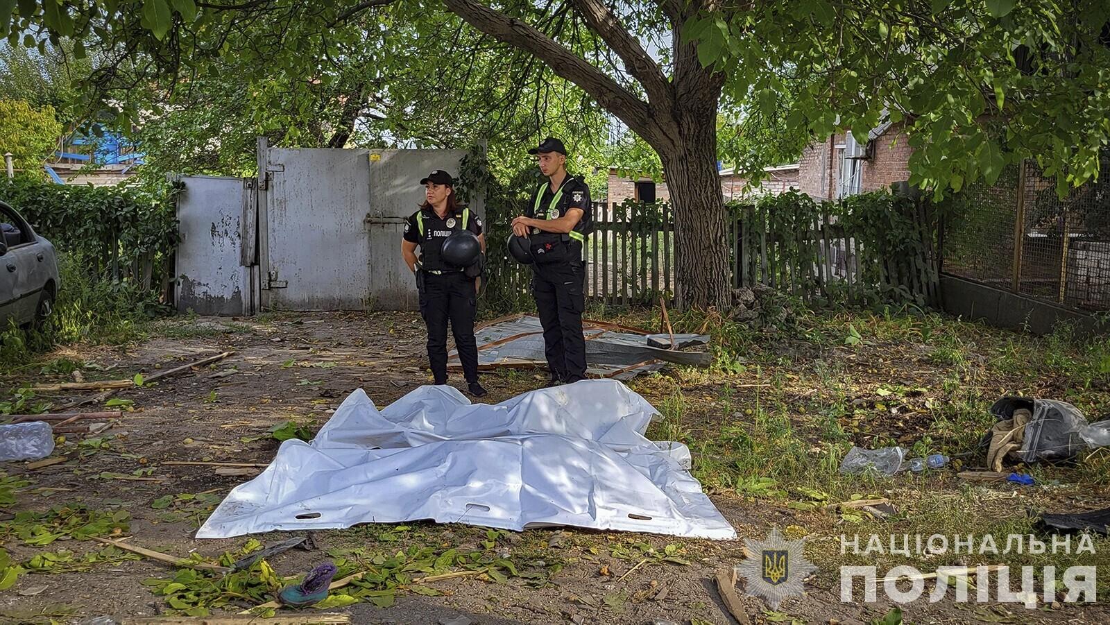 Policajti stoja pri obetiach ruského raketového útoku v Záporoží.